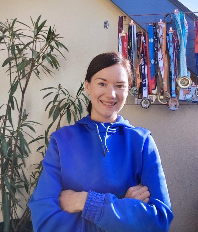 Portrait souriant d’Émilie Loiseau devant ses médailles de course